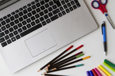 Dizüstü Pc ve kalem, renkli kalemler, gibi bazı nesneleri ucu kalem, makas beyaz masa üzerinde hissetti. Üstten Görünüm. Düz yatıyordu.