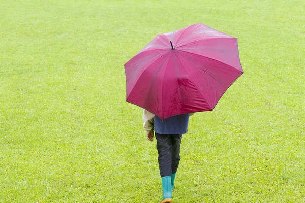 Niño con paraguas rojo bajo la lluvia. Vista trasera —  Fotos de Stock