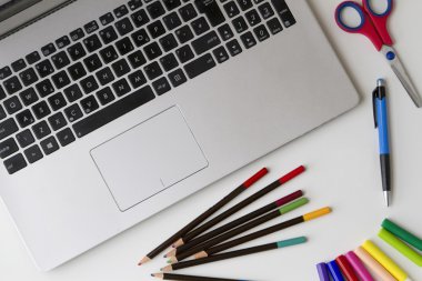 Laptop klavye ve kalem, renkli kalemler, gibi bazı nesneleri ucu kalem, makas beyaz masa üzerinde hissetti. Üstten Görünüm. Düz yatıyordu.