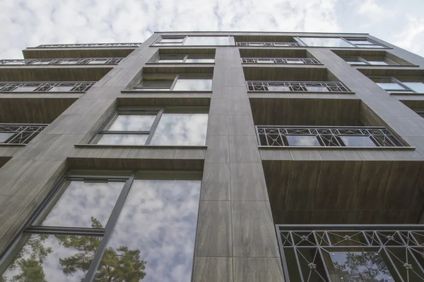 Edificio residencial sobre fondo celeste y reflejos de árboles en las ventanas — Foto de Stock