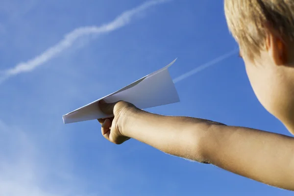 Criança com avião de papel contra o céu azul. Vista de ângulo baixo — Fotografia de Stock