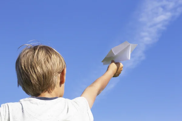 Rapaz com avião de papel contra o céu azul. Vista de ângulo baixo — Fotografia de Stock