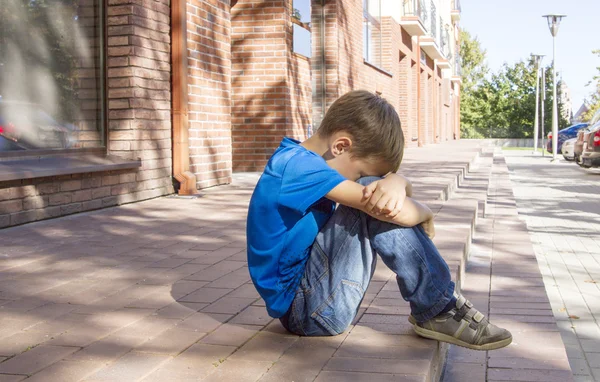 Triste, solitario, infeliz, niño decepcionado sentado solo en el suelo. Fondo de la ciudad. Exterior — Foto de Stock