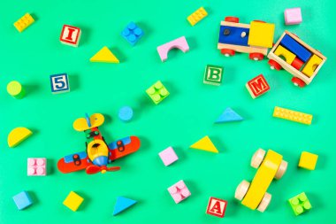 Açık yeşil arka planda renkli çocuk oyuncakları. Üst manzara, düz uzanma