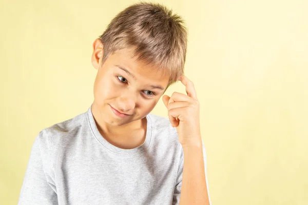 Pensando jovem menino de pé sobre luz amarelo fundo — Fotografia de Stock