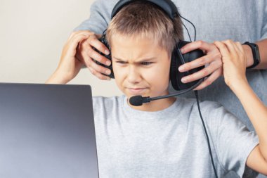 Anne öfkeli genç oğlunun kulaklıklarını çıkarıyor. Bilgisayar oyunları bağımlılığı