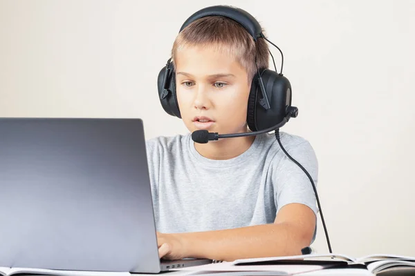 Um rapaz com auscultadores com computador portátil. Aprendizagem online, educação remota em casa — Fotografia de Stock