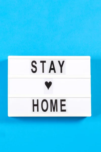 Caja de luz blanca con texto STAY HOME sobre fondo azul claro. Vista superior — Foto de Stock