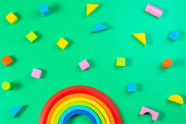 Baby Kinder Spielzeug Hintergrund. Holzstapeln Regenbogen und bunte Blöcke auf hellgrünem Hintergrund. Ansicht von oben — Stockfoto