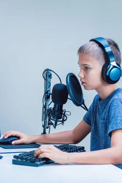 Retrato de adolescente usando fones de ouvido usando teclado e microfone de computador. Aprendizagem online, educação remota, jogo de vídeo, conceito de podcast — Fotografia de Stock