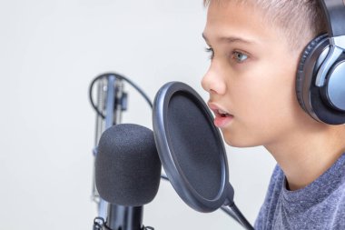 Mikrofon takan genç bir çocuğun portresi. Çevrimiçi öğrenme, uzaktan eğitim, video oyunu, podcast konsepti