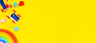 Bebek oyuncakları geçmişi. Tahta oyuncak tren, ahşap gökkuşağı ve sarı arka planda renkli bloklar. Üst manzara, düz uzanma