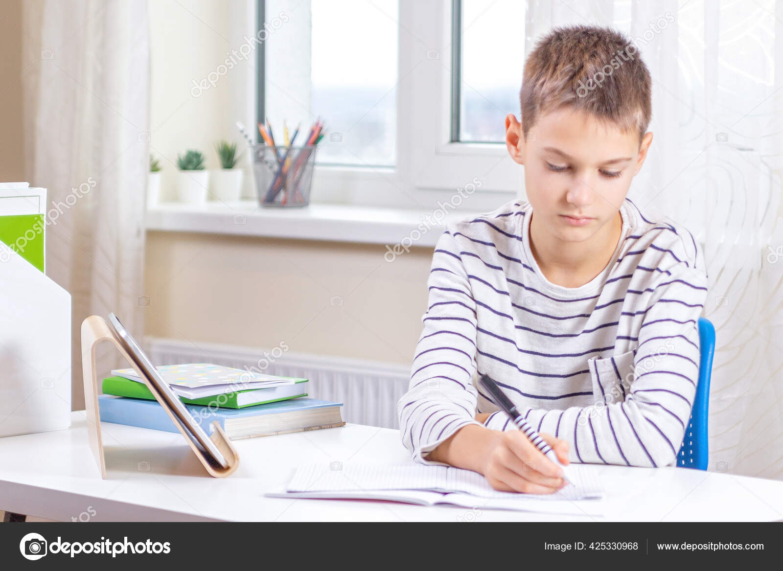 Kid with digital tablet computer writing, doing homework at white desk