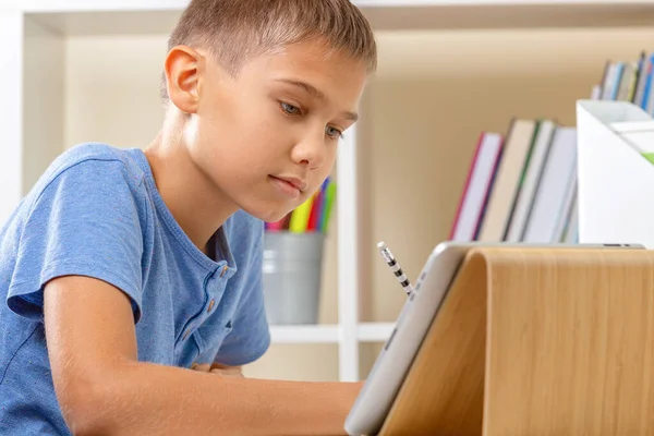 Adolescente com tablet digital escrevendo, fazendo trabalhos de casa na mesa branca. Aprendizagem online, educação remota, aulas à distância em casa — Fotografia de Stock