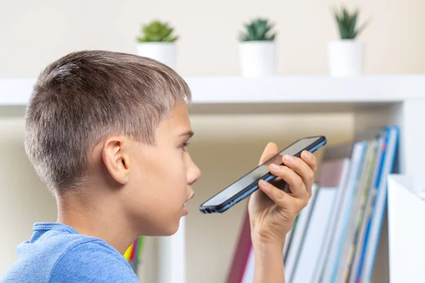 Adolescente fazendo lição de casa, usando gravação de celular e enviar uma mensagem de voz, fazendo chamada de voz — Fotografia de Stock