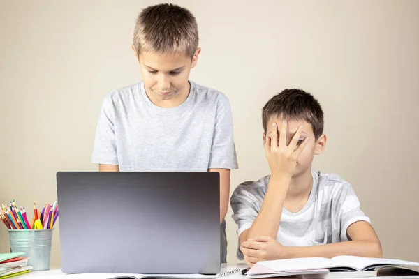 Dificuldades de aprendizagem, escola, educação remota, aprendizagem on-line em casa. Adolescente menino ajuda a triste irmão com tarefa de lição de casa — Fotografia de Stock