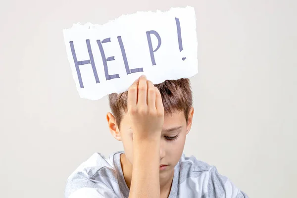 Triste cansado frustrado menino segurando rasgado cartão de papel com a palavra Ajuda. Dificuldades de aprendizagem, emoções infantis — Fotografia de Stock
