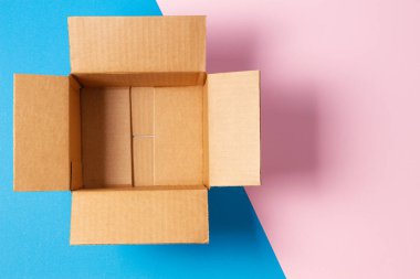 Geometrik pembe, açık mavi arka planda boş bir karton kutu. Üst görünüm
