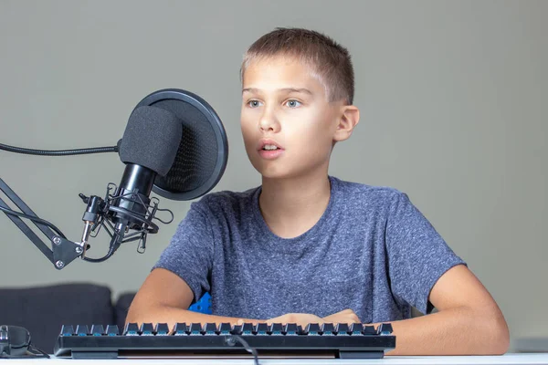 Um miúdo perto do computador a falar para o microfone. Tecnologia, aprendizagem online, educação à distância, educação à distância em casa — Fotografia de Stock