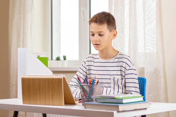 Παιδί με tablet υπολογιστή κάθεται στο τραπέζι με τα βιβλία και έχουν βιντεοκλήση, εικονική online leasson στο σπίτι — Φωτογραφία Αρχείου