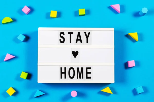 Evde kal. Mesajlı ışıklı kutu evde kal ve mavi arka planda tahta oyuncak blokları. Üst görünüm — Stok fotoğraf