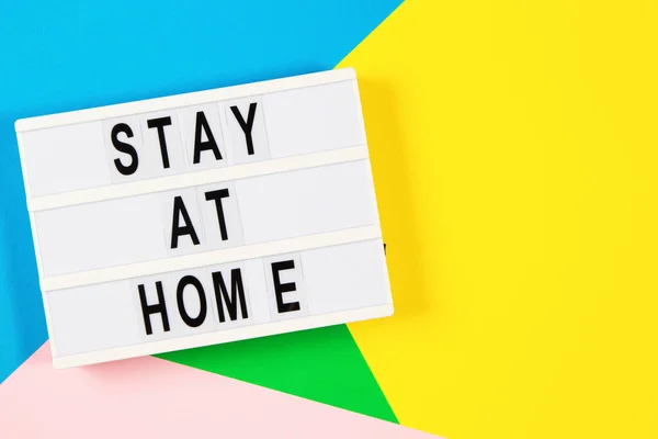 Lightbox con texto Quédese en casa sobre fondo amarillo, verde, rosa y azul claro. Vista superior —  Fotos de Stock