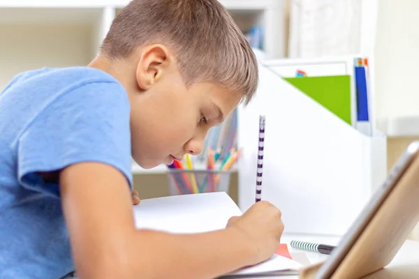 Adolescente con Tablet PC digital tiene lecciones sobre videollamada, haciendo la tarea en la mesa. Aprendizaje en línea, educación a distancia, lecciones a distancia en casa — Foto de Stock