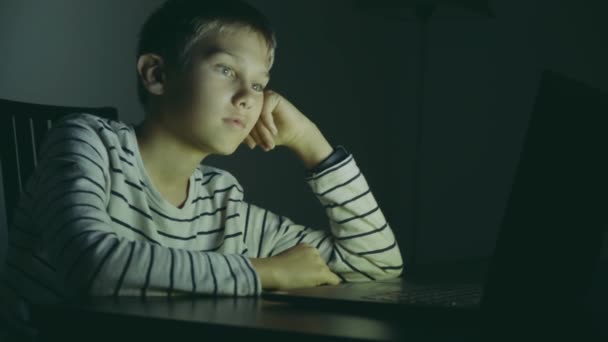 밤에 집에서 노트북 컴퓨터를 사용하는 10 대 소년. 어린 소년이 컴퓨터 게임을 하고, 비디오를 보고, 인터넷 서핑을 하고, — 비디오