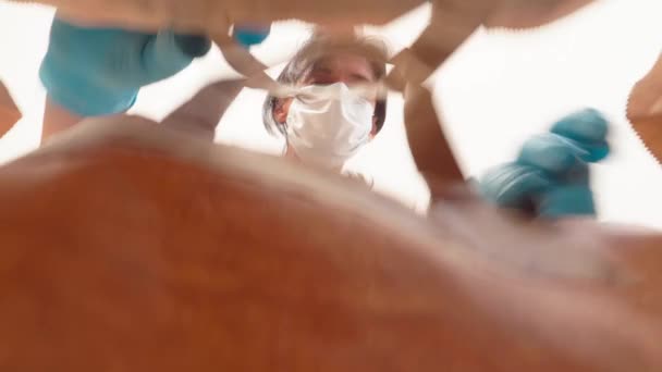 Woman with medical protective mask and latex gloves carefully opens paper shopping bag delivery from online store. Low angle view — Stock Video