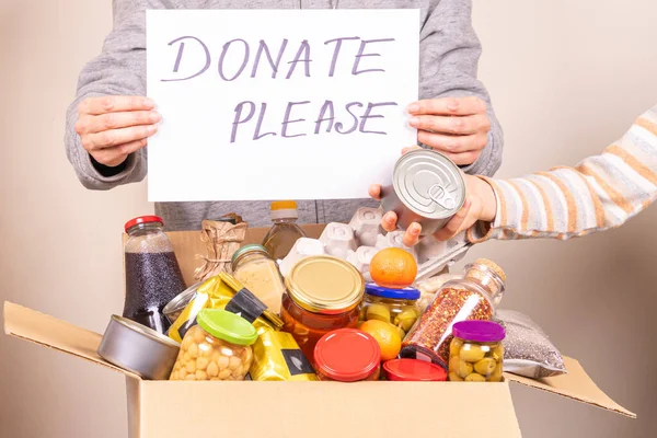 Voluntarios recogen productos de comestibles a la caja de donación de alimentos y la celebración de hoja de papel con el mensaje Gracias — Foto de Stock