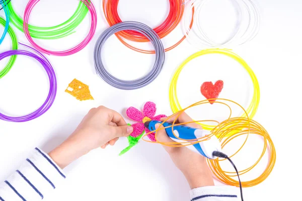 Kinderhände erstellen neue 3D-Objekte mit 3D-Stift. Lernen und Unterhaltung zu Hause. Ansicht von oben — Stockfoto