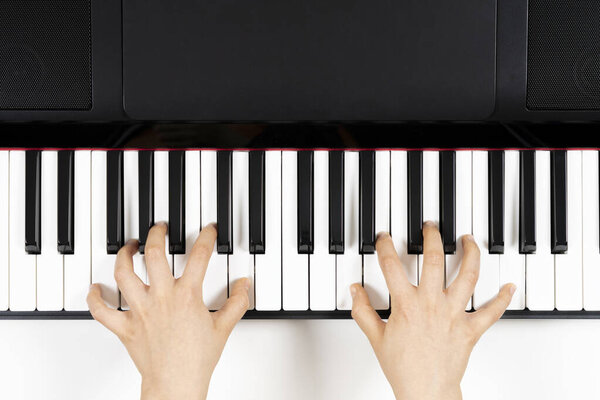 Kid hands learning to play on the piano. Top view