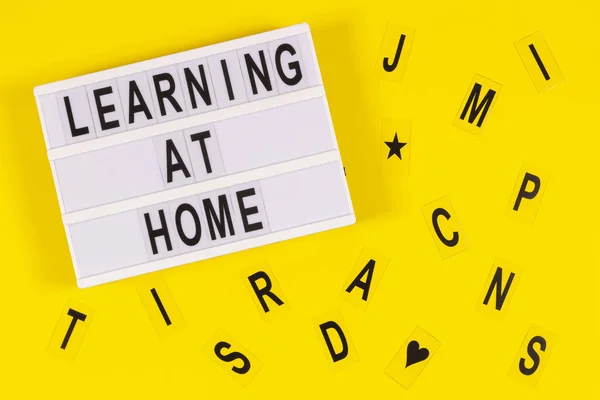 Aprendiendo en casa mensaje en lightbox y letras sobre fondo amarillo. Aprendizaje en línea, aprendizaje en el hogar, educación en el hogar, educación remota en el hogar concepto. Vista superior — Foto de Stock