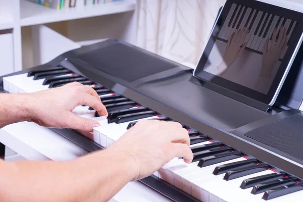 사람이 손으로 피아노를 연주하고 집에서 디지털 태블릿 컴퓨터로 비디오 튜토리얼을 보고 있는 모습 — 스톡 사진
