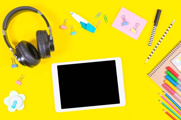 노란색 배경에는 태블릿 컴퓨터, 헤드폰, 학교 물품이 있다. 온라인 학습, 교육 배경 — 스톡 사진