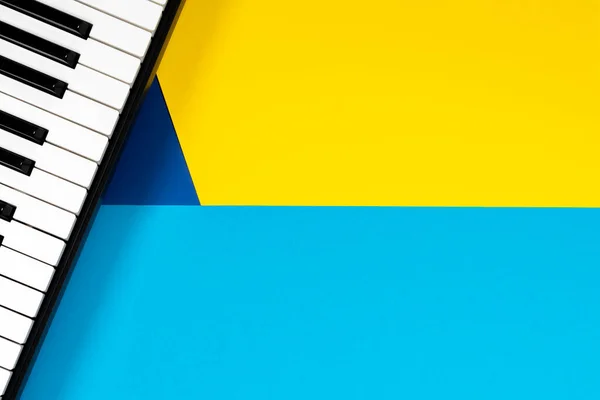 Vista superior al piano sobre fondo amarillo y azul. Concepto de aprendizaje musical. Vista superior —  Fotos de Stock