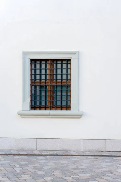 Urbaner Hintergrund. Weiße Wand mit kleinem Fenster und Eisengitter — Stockfoto