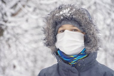 Çocuk koruyucu maske takıyor ve dışarıda eğleniyor. Aktif kış tatili, Corona virüsü salgını süresince eğlence