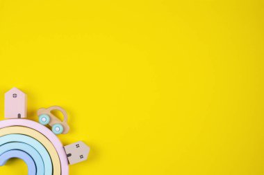 Oyuncak gökkuşağı, renkli evler ve sarı arka planda ahşap bir araba. Üst görünüm