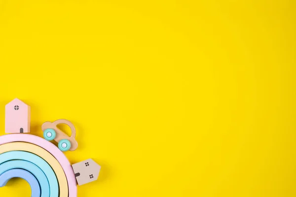 Toy rainbow, colorful houses and wooden car on yellow background. Top view — Stock Photo, Image