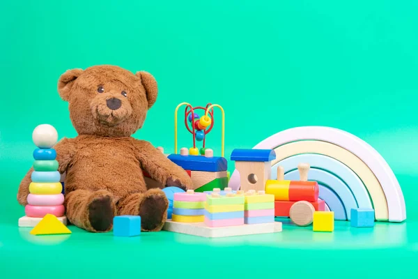 Gyerekjátékok gyűjteménye. Teddy mackó, fa szivárvány, vonat és baba játékok világoszöld háttér — Stock Fotó