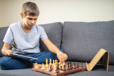 Genç çocuk tablet bilgisayarla online satranç oynamayı öğreniyor. Çevrimiçi eğitim, uzaktan öğrenme, evde eğlence