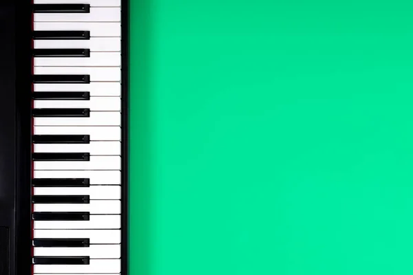 Açık yeşil zemin üzerinde siyah piyano klavyesi. Müzik öğrenme konsepti. Üst görünüm — Stok fotoğraf