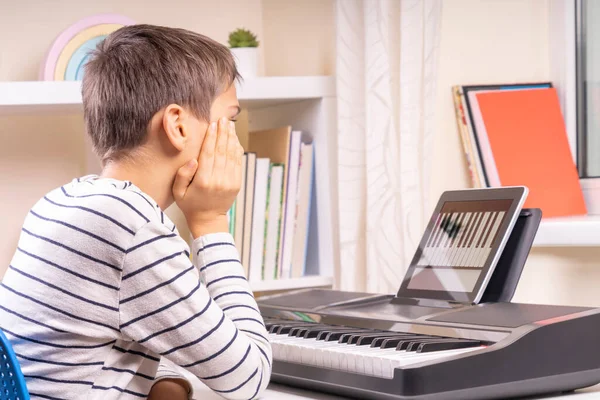 Εφηβικό αγόρι που παρακολουθεί μαθήματα βίντεο στον υπολογιστή tablet και μαθαίνει να παίζει ψηφιακό πιάνο στο σπίτι. Ηλεκτρονική μάθηση εξ αποστάσεως εκπαίδευση — Φωτογραφία Αρχείου