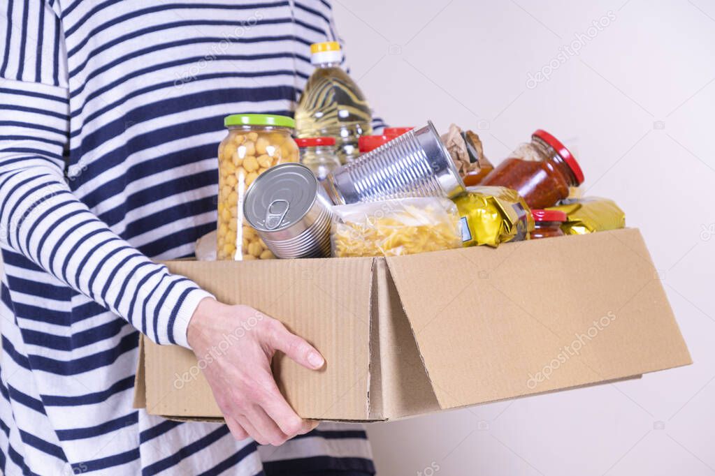 Woman volunteer hands holding food donations box with food grocery products