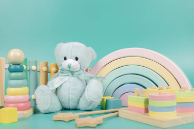 Oyuncak ayı, tahta gökkuşağı, eğitim ve müzik oyuncakları açık mavi arka planda