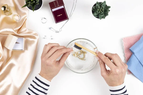 Kadın elleri temizleme ve mücevher kolyesini ev yapımı kuyumcu ile parlatıyor. Üst görünüm