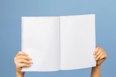 Gri arkaplan üzerinde boş bir defter tutan eller. Boş kitap, okul defteri, günlük sunum şablonu