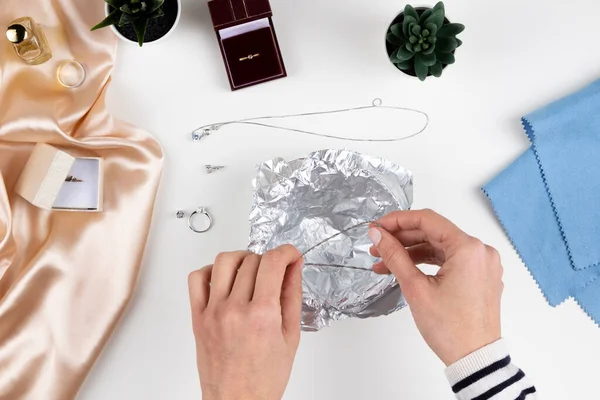 Kadın elleri evde gümüş mücevherleri ev yapımı kuyumcuyla temizliyor. Üst görünüm