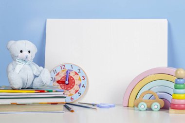 Oyuncak bebekler, oyuncak ayılar, kitaplar, okul malzemeleri ve beyaz masadaki büyük boş defterler. Okula, eğitime, anaokuluna, anaokuluna.